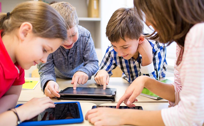 Kinder arbeiten gemeinsam im Unterricht und mit Tablets