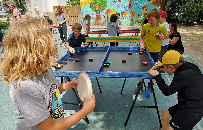 Kinder spielen Tischtennis oder ein ähnlich gelagertes Spiel.
