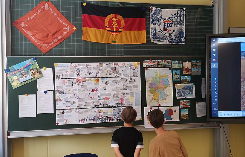 Zwei Jungen stehen vor einer Informationstafel zum Thema DDR.