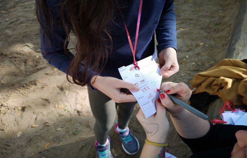 Eine Schülerin der DPFA Grundschule Leipzig lässt sich beim Weitsprung von einer Erzieherin der Fachschule für Soziales der DPFA Leipzig dieerreichte Weite auf ihrer Stempelkarte eintragen.
