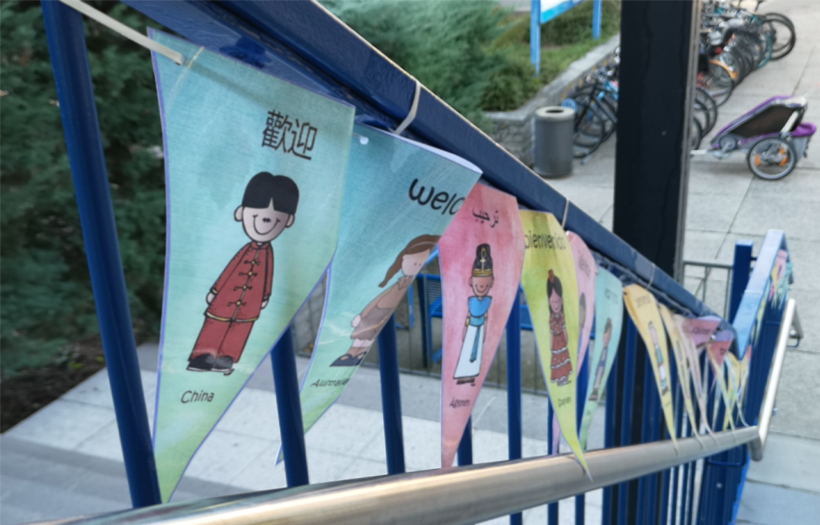 Am Eingang der Grundschule zeigt eine Fahnenkette unterschiedliche Kinder unterschiedlicher Nationalitäten.