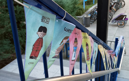 Am Eingang der Grundschule zeigt eine Fahnenkette unterschiedliche Kinder unterschiedlicher Nationalitäten.
